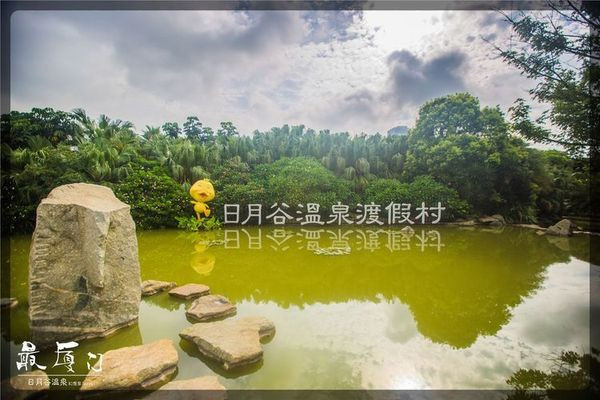 正门口由一弯湖水和景观石块设计组成,"日月谷温泉度假村"在水面的