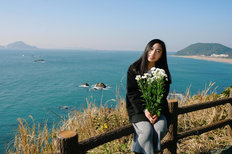 在当地的早市上买了一束白色的雏菊,拿着花在海边拍一张照片留念,这次