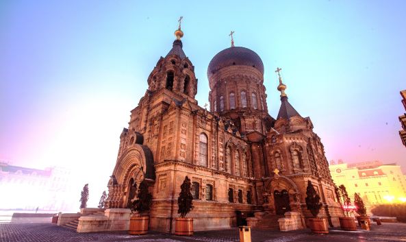 <p>始建于1907年的圣索菲亚大教堂是哈尔滨的地标性建筑，它那绿色的洋葱头式大穹顶十分引人注目，这座宏伟的拜占庭式建筑虽然已不再具有教堂的功能，但作为哈尔滨最漂亮的异域风格建筑，它仍吸引着众人慕名前来参观。</p><p>圣索菲亚大教堂曾经是远东地区最大的东正教堂，目前是中国保存最完整的拜占庭式建筑，虽然在1997年就更名为&ldquo;哈尔滨市建筑艺术馆&rdquo;，但是无论当地人，还是外地游客，更愿意称它为&ldquo;索菲亚大教堂&rdquo;。</p><p>这座教堂最引人注目的部分，是那饱满而巨大、高达48米的洋葱头式的大穹顶，这种典型俄罗斯建筑风格的屋顶形式，宏伟壮观，可以同莫斯科的瓦西里升天大教堂相媲美。教堂的墙体采用清水红砖，大穹顶周围是四个大小不同的帐蓬顶，四个顶下的楼层之间有楼梯相连，整个教堂前后左右有四个门出入。正门顶部为钟楼，内有7座铜铸制的乐钟（据说已经遗失）。</p><p>教堂改建成艺术馆后，进行了内部改建，通过展示近千幅图片和城市规划沙盘，反映了名城哈尔滨的历史、现状与未来。不过改建后，原有的格局被破坏了，作为教堂的功能也已经消失了。如果游客只是对建筑和教堂感兴趣，可以不必入内参加。</p><p>教堂前的广场有&ldquo;广场鸽&rdquo;，还设有大型系列音乐喷泉，当地人非常喜欢在这里拍婚纱照。与白天相比，教堂的夜景更美丽，每当夜幕降临时，在灯光的承托下，教堂更显得雄伟神秘，充满异国情调。</p><p>从圣索菲亚大教堂出发，步行约10分钟，可以到<a href="http://you.ctrip.com/sight/haerbin151/7712.html">中央大街</a>。</p>